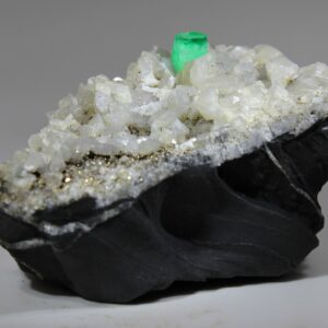 Green emerald on calcite and dark sedimentary matrix from Muzo, Colombia