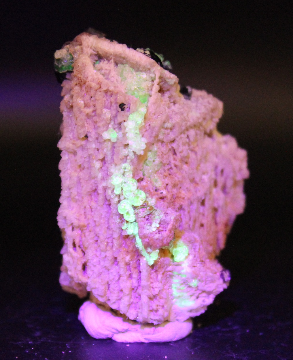 Gelbgrün fluoreszierender Glasopal auf Feldspat unter langwelligem UV-Licht