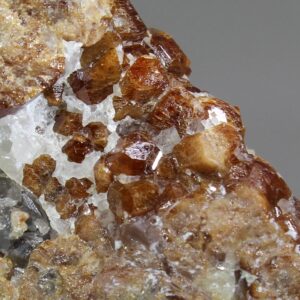 Detailaufnahme honigbrauner Hessonit-Kristalle auf weißem Quarz