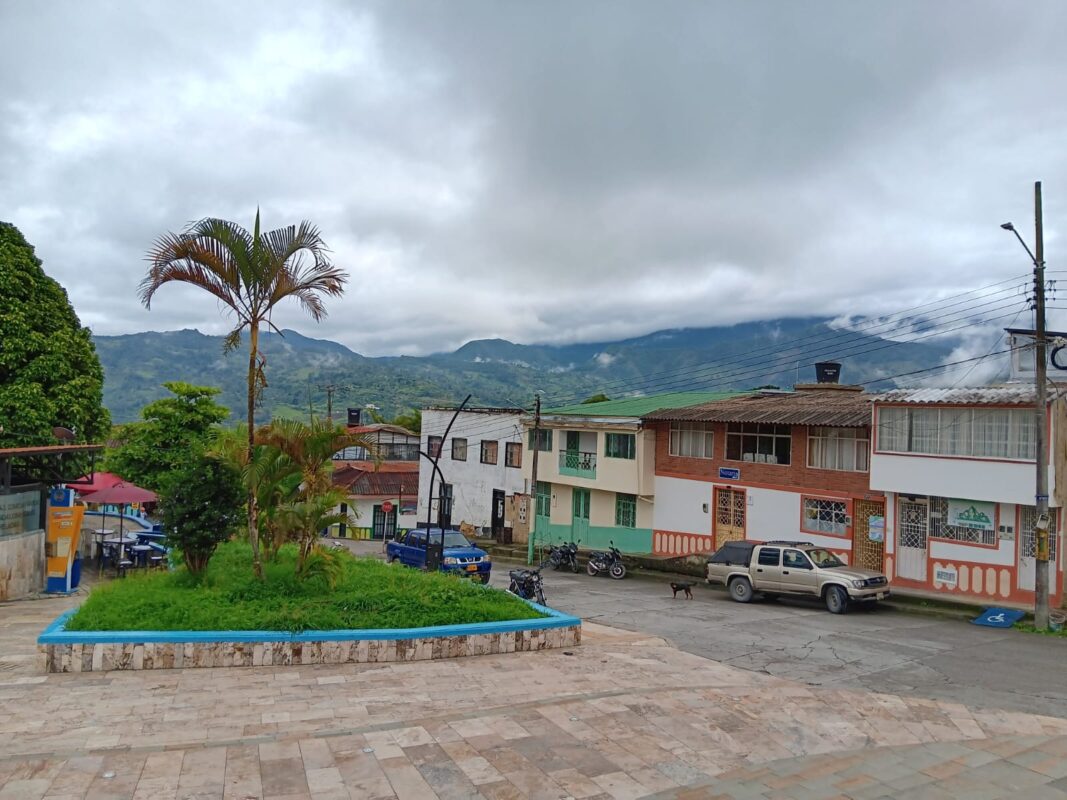 Blick über die Plaza von Gachalá mit umliegenden Häusern und den wolkenverhangenen Berghängen der Ostkordillere im Hintergrund.