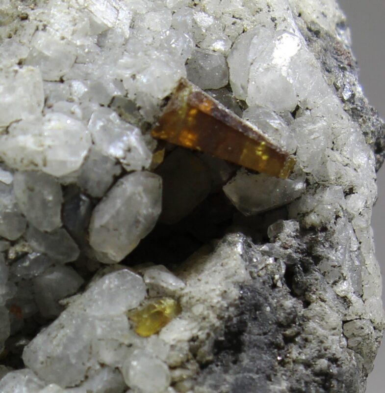 Parisite-(Ce) on light-colored calcite matrix from the Muzo District, with a brown to golden-yellow crystal freely exposed on the hydrothermal vein mineralization